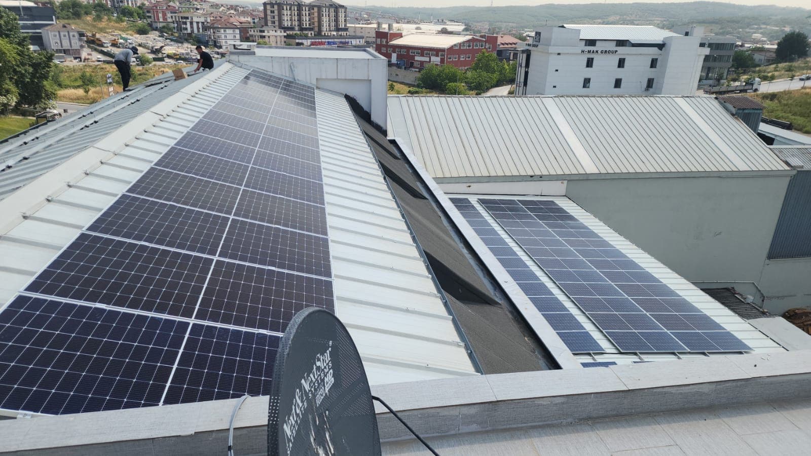 Geniş fabrika çatısındaki tamamlanmış güneş enerjisi sistemi