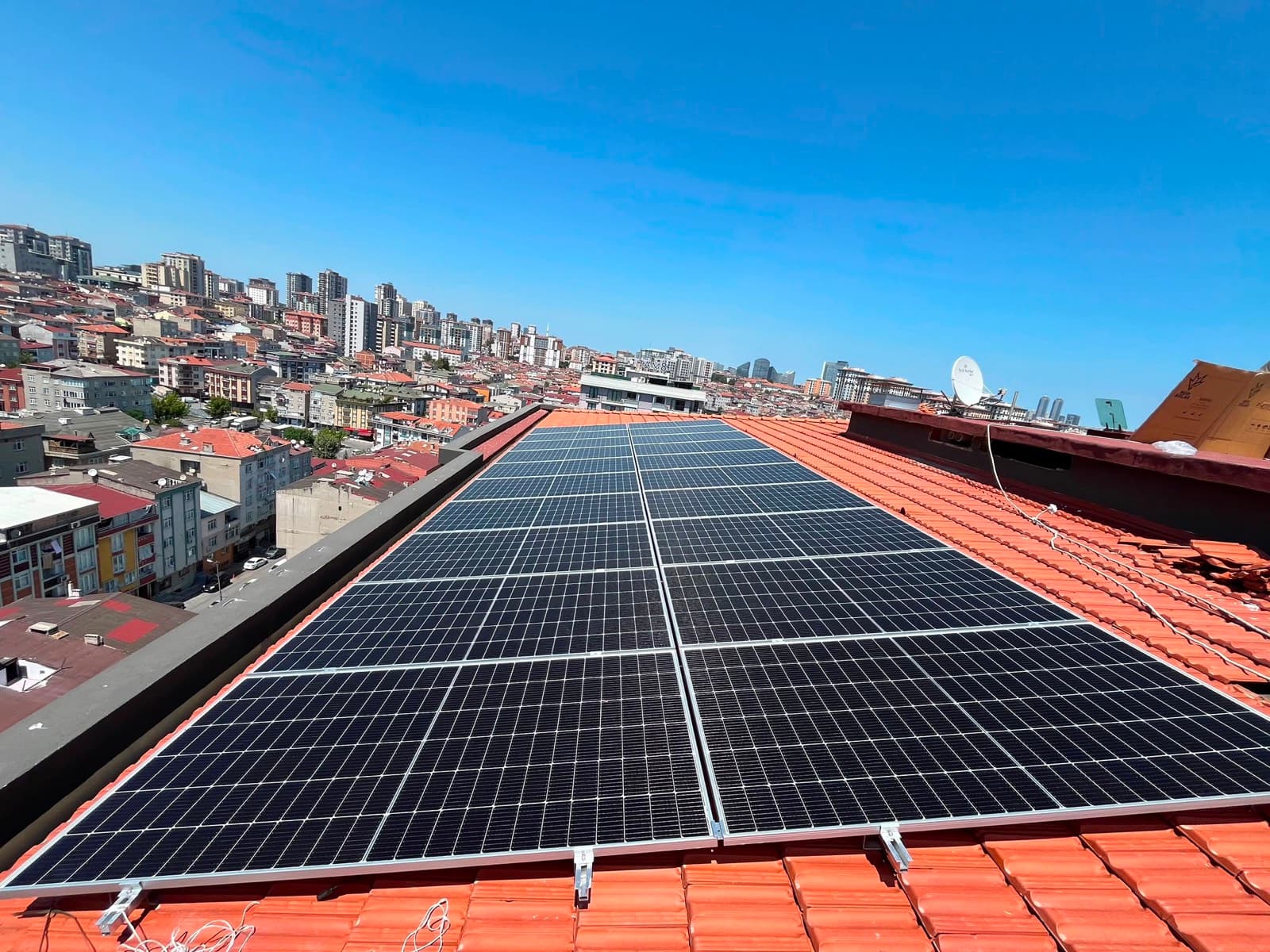 İstanbul'da kiremit çatıya kurulmuş on grid sistem ve arkasında şehir silüeti